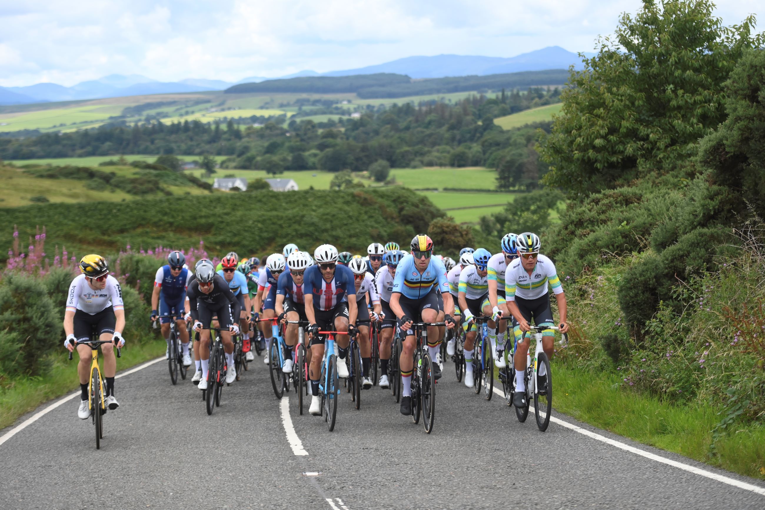 The peloton, led on one side by Lucas Plapp, in the elite men road race at the 2023 UCI Road World Championships from Edinburgh to Glasgow, Scotland